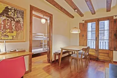 a dining room with a table and chairs and a bedroom at Alcam Sombrerers in Barcelona