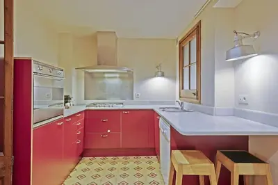 a kitchen with red cabinets and white counter tops at Alcam Sombrerers in Barcelona