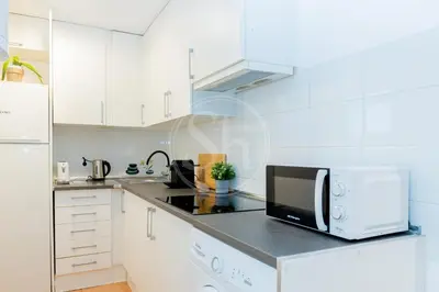 a kitchen with white cabinets and a microwave at Estudio en Eixample in Barcelona
