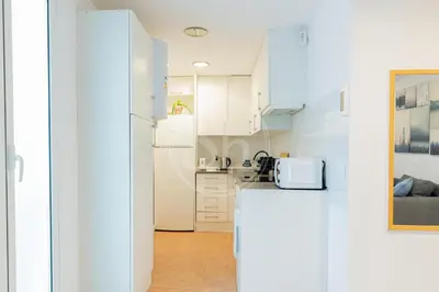 a kitchen with white cabinets and a refrigerator at Estudio en Eixample in Barcelona