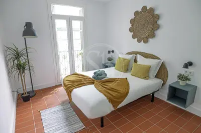 a bedroom with a bed with white sheets and yellow pillows at Maravilloso apartamento en Poble Sec in Barcelona