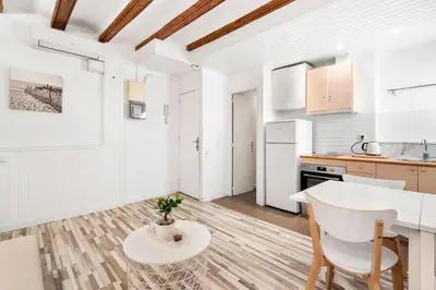 a white kitchen with a table and a dining room at Charming Beachside Apartment in Barceloneta in Barcelona