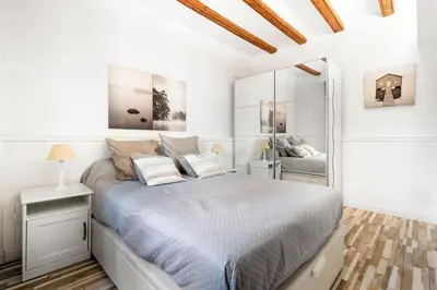 a white bedroom with a bed and a mirror at Charming Beachside Apartment in Barceloneta in Barcelona