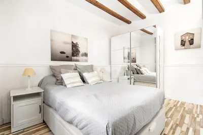 a white bedroom with a bed and a mirror at Charming Beachside Apartment in Barceloneta in Barcelona