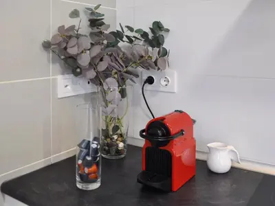 a table with a vase with flowers and a toaster at Casa familiar luminosa con piscina, cerca de la playa y parques, ideal para 6 personas en Cubelles - ES-332-5 in Cubelles