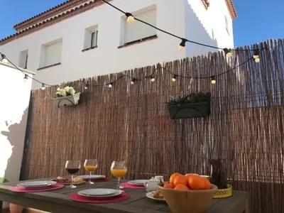 a table with a bowl of oranges and wine glasses at Casa familiar luminosa con piscina, cerca de la playa y parques, ideal para 6 personas en Cubelles - ES-332-5 in Cubelles