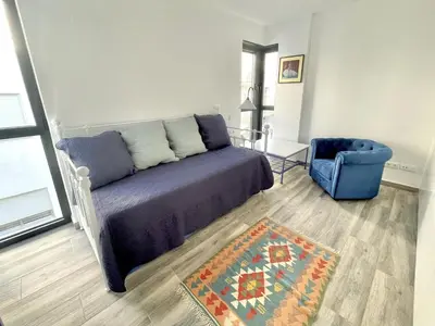 a bedroom with a bed and a blue chair at Apartamento Confortable con Parking Privado en el Centro de Vilanova i la Geltrú - ES-332-8 in Vilanova i la Geltrú