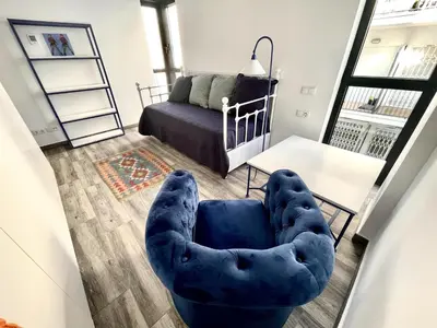 a living room with a blue chair and a couch at Apartamento Confortable con Parking Privado en el Centro de Vilanova i la Geltrú - ES-332-8 in Vilanova i la Geltrú