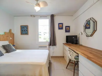 a bedroom with a bed and a desk with a television at Balcis Apartment by Hello Homes Sitges in Sitges