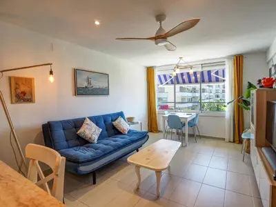 a living room with a blue couch and a table at Balcis Apartment by Hello Homes Sitges in Sitges