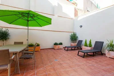 a patio with a table and chairs and a green umbrella at Key San Pau House Terrace - Barcelona in Barcelona