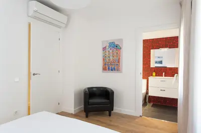 a bedroom with a black chair and a red brick wall at Key San Pau House Terrace - Barcelona in Barcelona