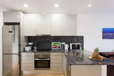 a kitchen with white cabinets and a granite counter top at Key San Pau House Terrace - Barcelona in Barcelona