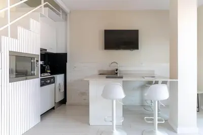 a kitchen with a sink and a counter with two stools at Penthouse with private terrace in the center in Barcelona