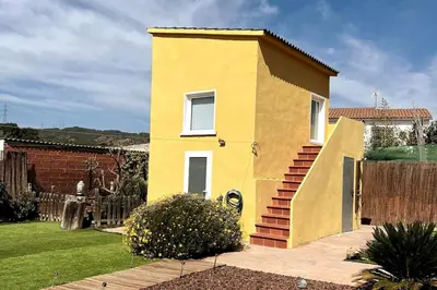a yellow house with a staircase in a yard at Casa Salud in Piera