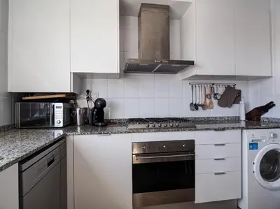 a kitchen with white cabinets and a stove top oven at Panoramic Terraces by Hello Homes Sitges in Sitges