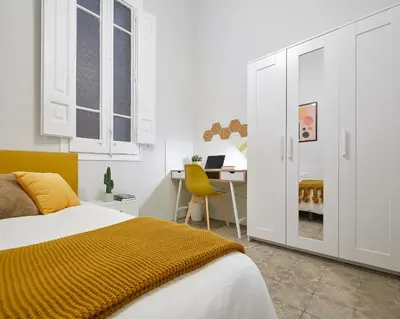 a bedroom with a bed and a desk with a laptop at Girona 46 - 1 in Barcelona