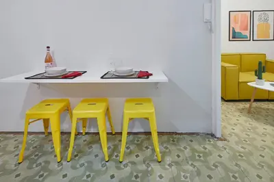 two yellow stools sitting next to a counter with a table at Girona 46 - 1 in Barcelona