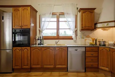 a kitchen with wooden cabinets and a window at Casa Fontanals in Pla del Panadés