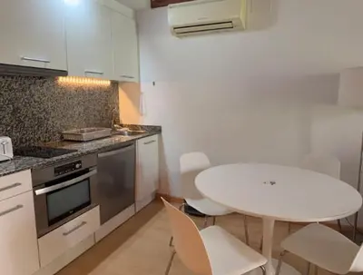 a kitchen with a table and a white table and chairs at Homenfun Barcelona Hospital Clínic l in Barcelona