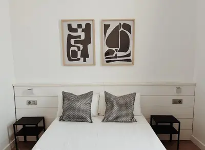 a bedroom with a white bed with two black and white pillows at Apartamentos Express by gaiarooms in Barcelona