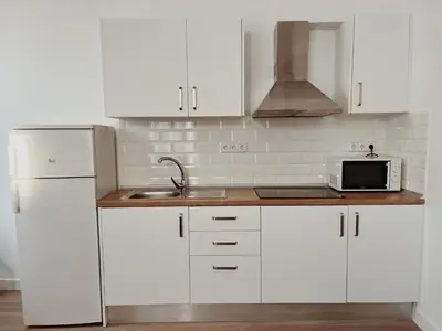 a kitchen with white cabinets and a sink and a microwave at Apartamentos Express by gaiarooms in Barcelona