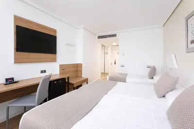 a white bedroom with a large bed and a desk at Alexandre FrontAir Congress in Sant Boi del Llobregat