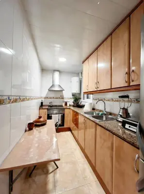 a large kitchen with wooden cabinets and a sink at Mi casa es tu casa in Hospitalet de Llobregat