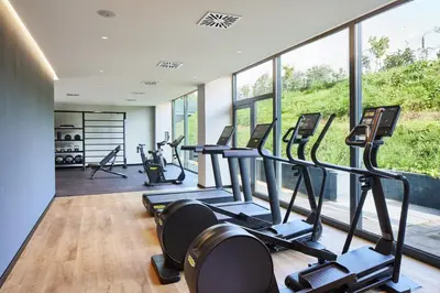 a gym with treadmills and ellipticals in a room with windows at Four Points by Sheraton Barcelona Airport in Barcelona