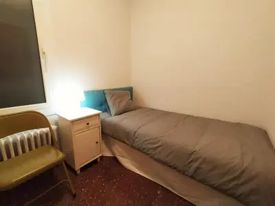 a small bedroom with a bed and a chair at Spacious apartment in the heart of the city in Barcelona