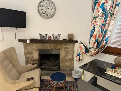 a living room with a fireplace and a clock on the wall at Hidden Garden Haven for 7 People in Vallromanas
