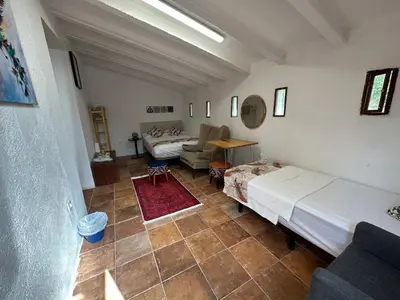 a bedroom with two beds and a living room with a couch at Hidden Garden Haven for 7 People in Vallromanas