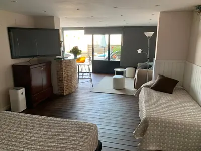 a bedroom with two beds and a flat screen tv at Apartamento con piscina y barbacoa cerca de Barcelona in Teià