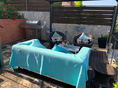 a patio with a blue couch and a grill at Apartamento con piscina y barbacoa cerca de Barcelona in Teià