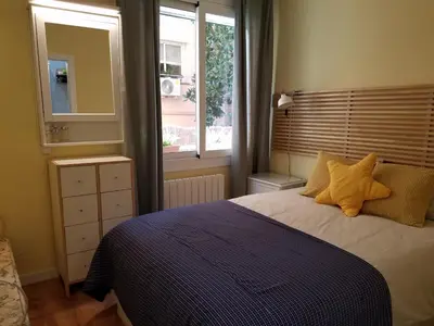a bedroom with a bed with yellow pillows and a window at Apart 2 bedrooms 2 bathroom 30 nigth min WiFi washmachime elevator AC heather in Barcelona