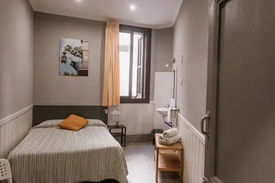 a small room with a bed and a sink at Pensión 45 in Barcelona