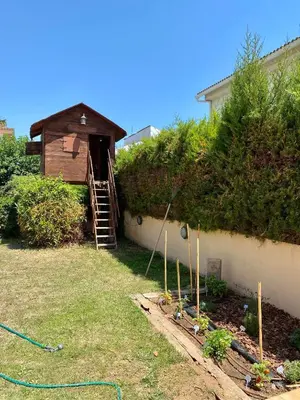 a garden with a wooden house with a staircase and plants at Villa Isabel Sitges, Rocamar in Sant Pere de Ribes