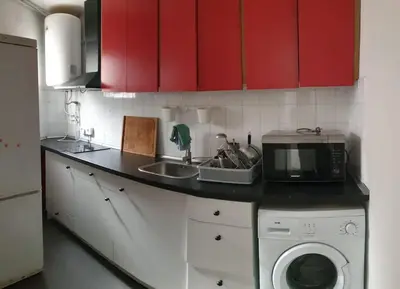 a kitchen with red cabinets and a sink and a microwave at Apartment 3 minutes from the beach and train station on foot in Canet de Mar