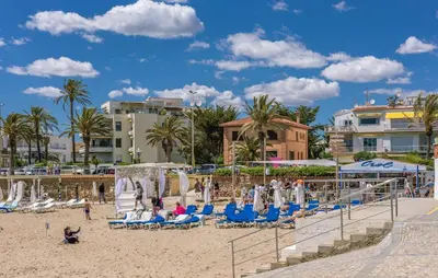 a beach with chairs and palm trees and buildings at Amazing Apartment In Sant Pere De Ribes in Sant Pere de Ribes