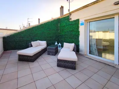 a patio with two wicker seats and a green wall at Casa en alquiler vacacional Vilanova i la Geltrú in Vilanova i la Geltrú