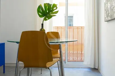 a glass table with two chairs and a potted plant at Alojamiento en el barrio de gracia in Barcelona