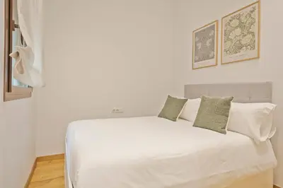 a white bed with four pillows on top of it at Aspasios Arc de Triomf Apartments in Barcelona