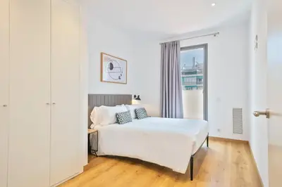 a white bedroom with a bed and a window at Aspasios Arc de Triomf Apartments in Barcelona