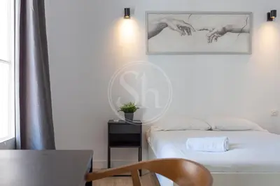 a bedroom with a bed and a table and a chair at Céntrico apartamento familiar in Barcelona