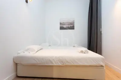 a bedroom with a bed with white sheets at Céntrico apartamento familiar in Barcelona