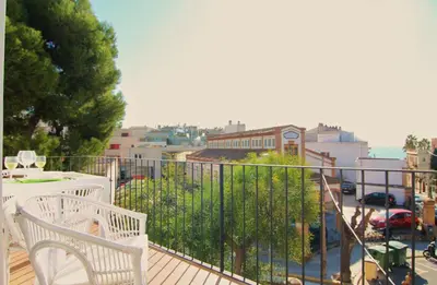 a balcony with a white bench and a view of a city at Mediterrani Vacaciones perfectas y vistas al mar in Sitges