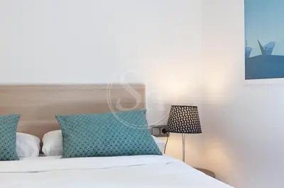 a bedroom with a bed with blue pillows and a lamp at Cómodo apartamento para dos en el Eixample in Barcelona