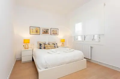 a white bedroom with a white bed and two lamps at Apartamento Familiar junto a Hospital Clinic in Barcelona