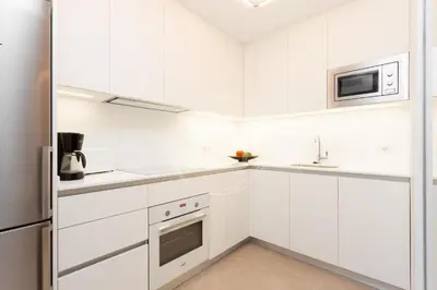 a white kitchen with white cabinets and a sink at Apartamento Familiar junto a Hospital Clinic in Barcelona