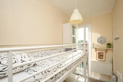 a white bed in a white room with a clock at The Sants's balcony in Barcelona